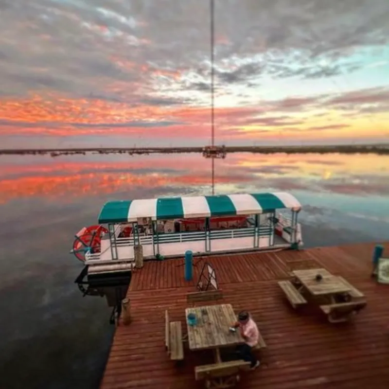 a wooden boat in a body of water with a swamp sunset in the background